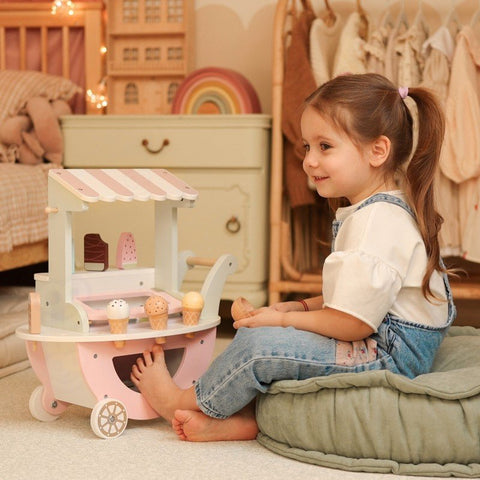 1. Child sitting on cushion playing with pastel wooden ice cream cart in cozy playroom