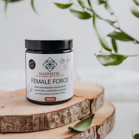 1. MaiWistik FEMALE FORCE Body Scrub 180ml jar displayed on wooden surface with green leaves, highlighting natural ingredients and Estonian craftsmanship