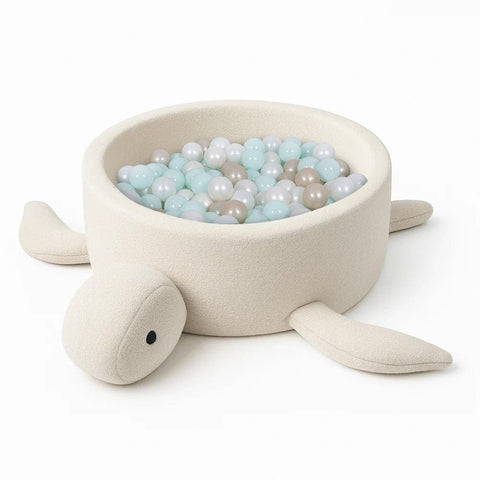 2. Turtle-shaped baby ball pit in cream beige boucle fabric filled with pastel blue and beige balls, shown in studio setting