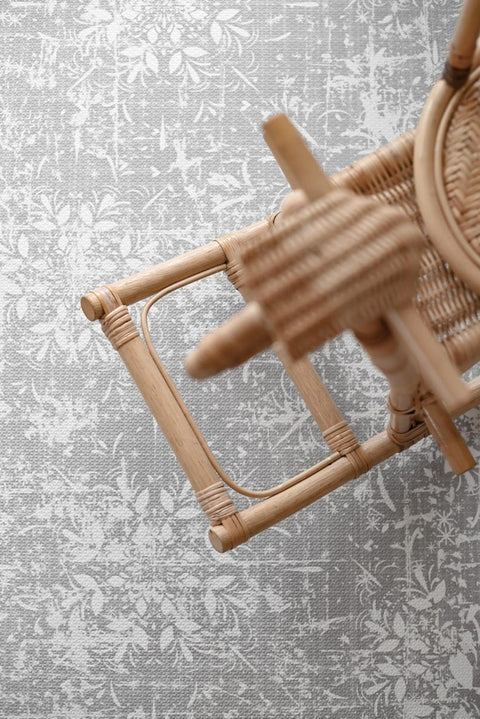 3. Close-up of wicker chair on OLYA KIDS vintage grey foam puzzle playmat showing intricate floral pattern