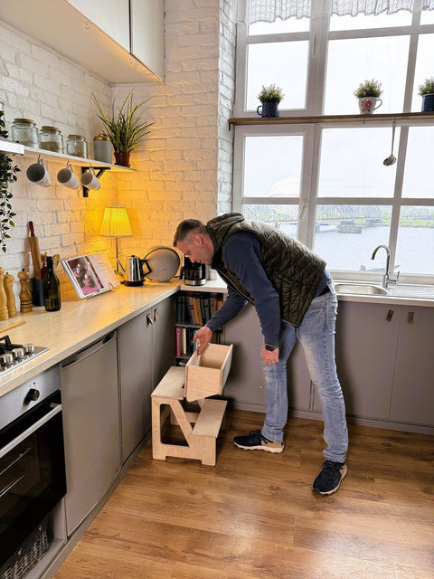 1. Man using wooden folding seat and climbing helper in kitchen to reach shelf