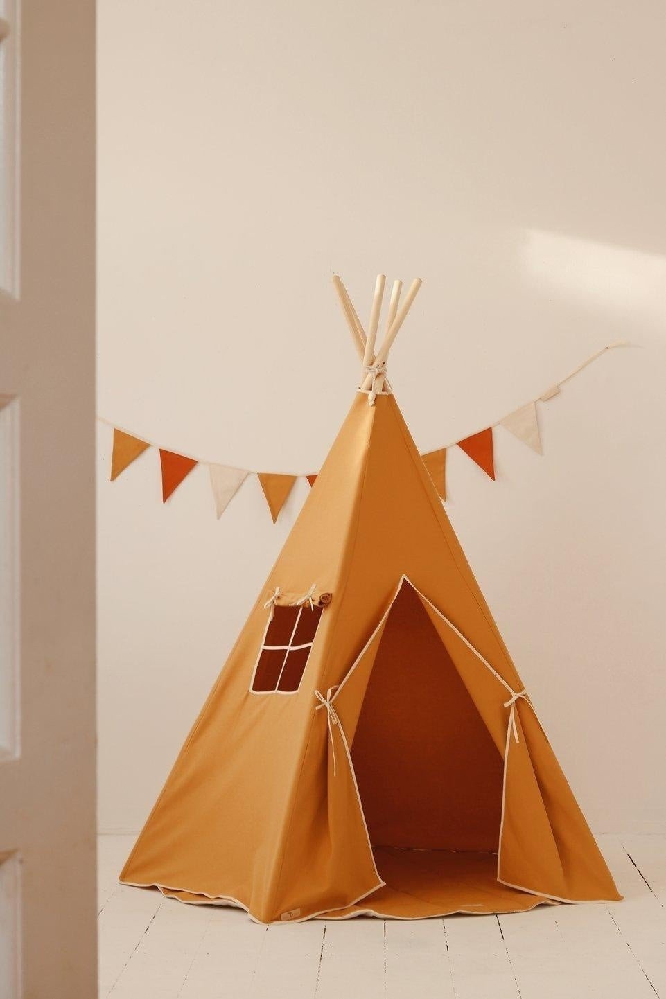 1. Ochre garland with white, honey, and red pennants hanging above a children's tepee in a room