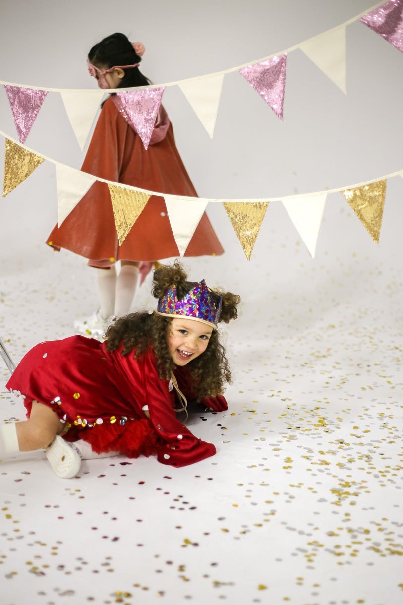 1. Two children playing with gold and beige sequin garland in festive setting with confetti