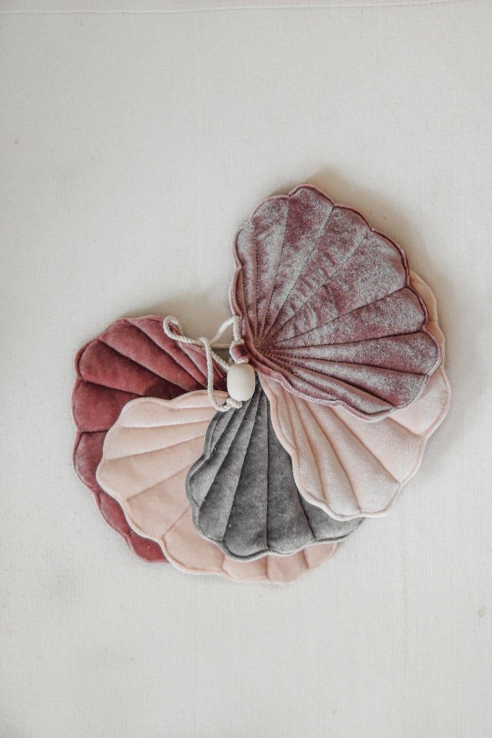 3. Close-up of folded velvet shell garland in marsala, pastel apricot, and grey on a light background
