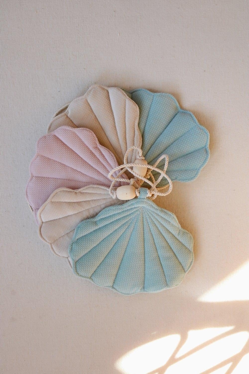 7. Close-up of pastel velvet shell pendants stacked together on a light surface