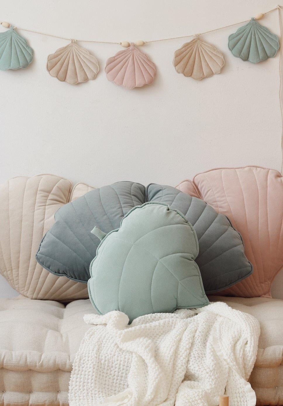 6. Close-up of pastel shell garland hanging above shell-shaped cushions in a cozy seating area
