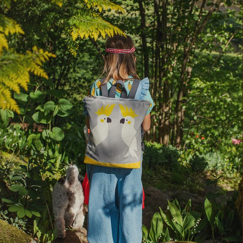 1. Girl wearing Muni Cockatoo kids backpack in garden setting, showcasing playful design