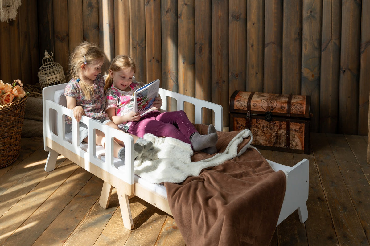 8. Two children reading on white growing bed with brown blanket in rustic wooden room