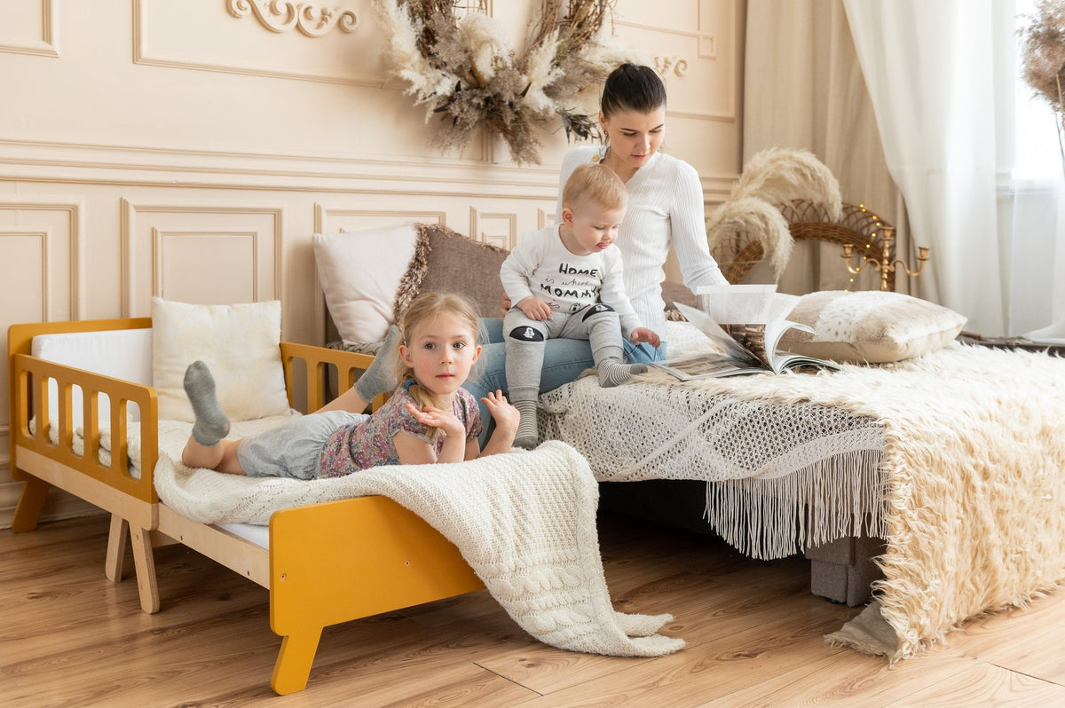 2. Woman with two children on yellow growing bed and large bed in cozy room with decorative elements