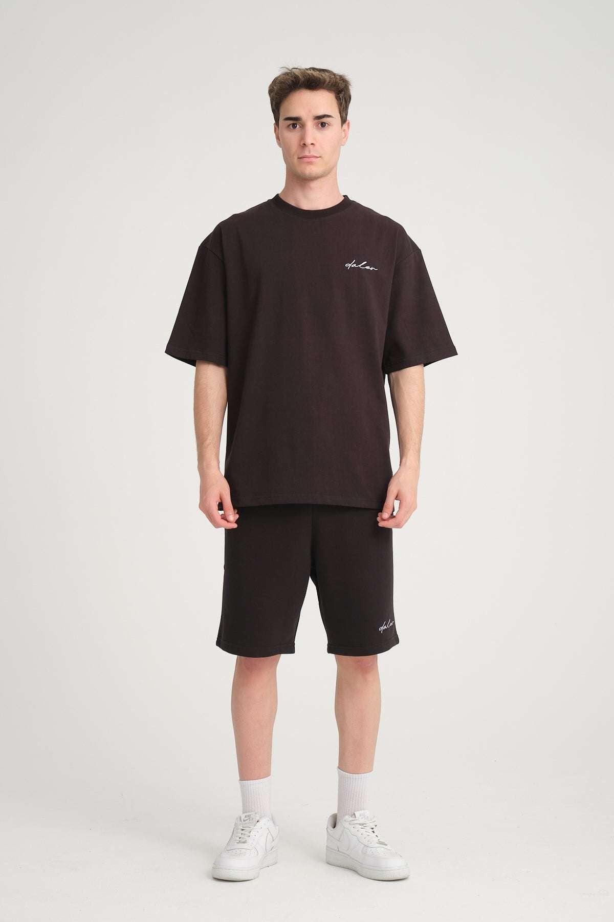 1. Man wearing black oversized DalerClo t-shirt and shorts with white sneakers in studio setting