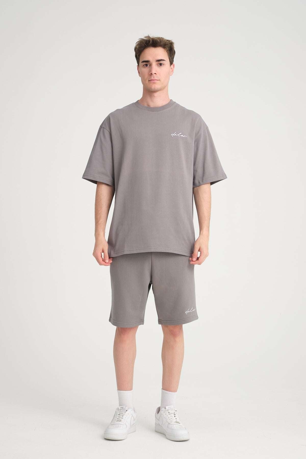 4. Front view of man wearing grey oversized t-shirt and shorts, standing in studio