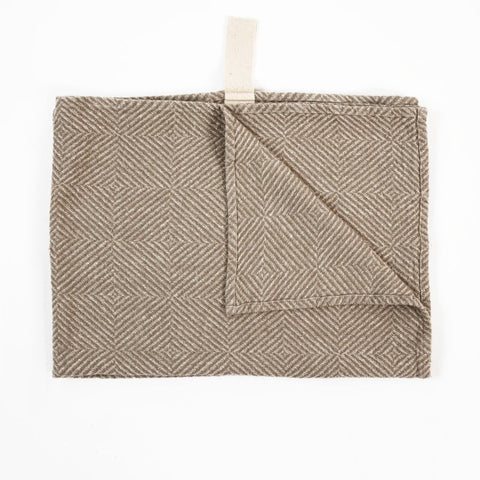 2. Beige linen towel with checkered fishbone pattern, partially folded, with white cotton hanger on white background