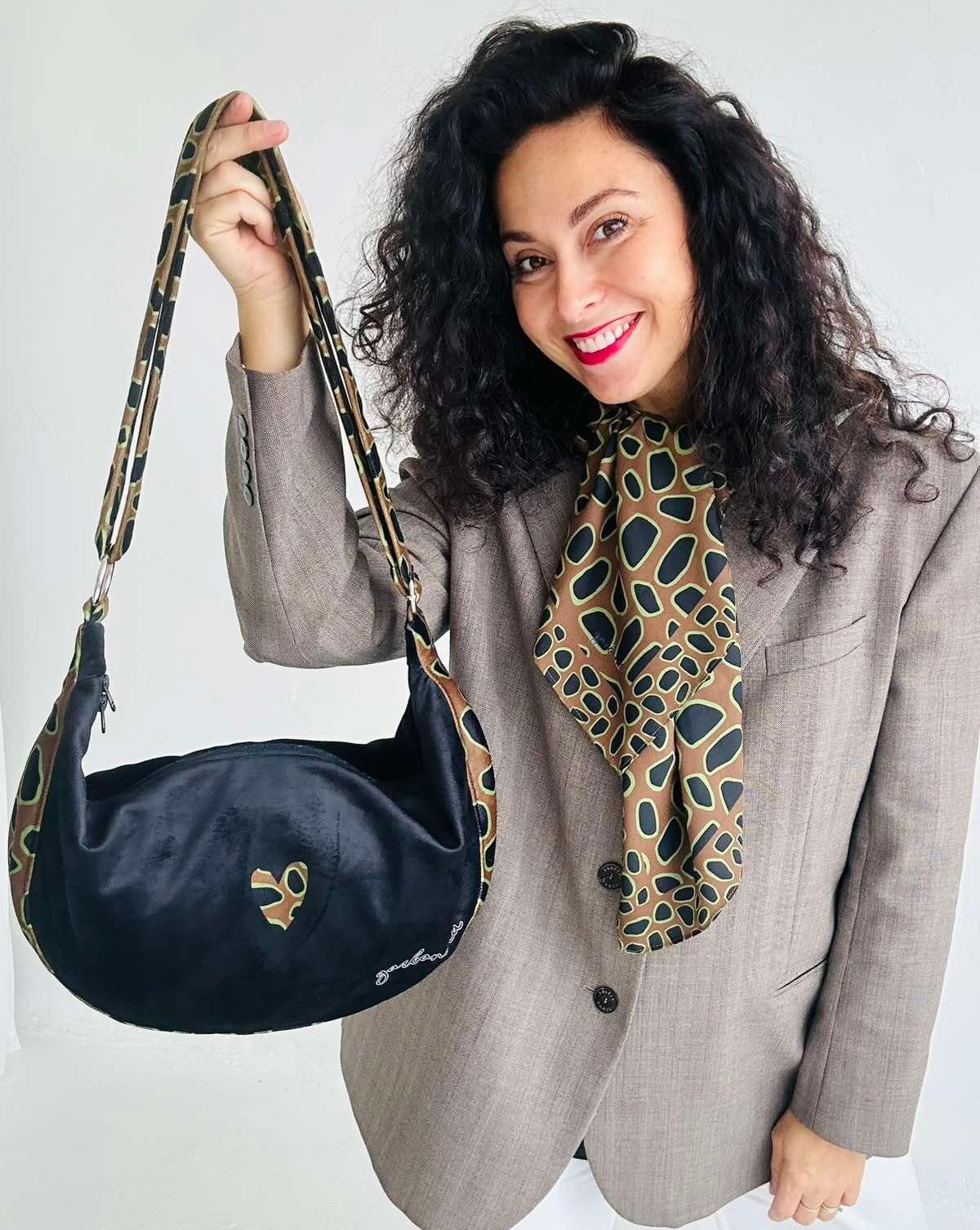 1. Woman holding Garbanota Hobo Bag - Leopard Heart in studio, showcasing adjustable strap and velour exterior