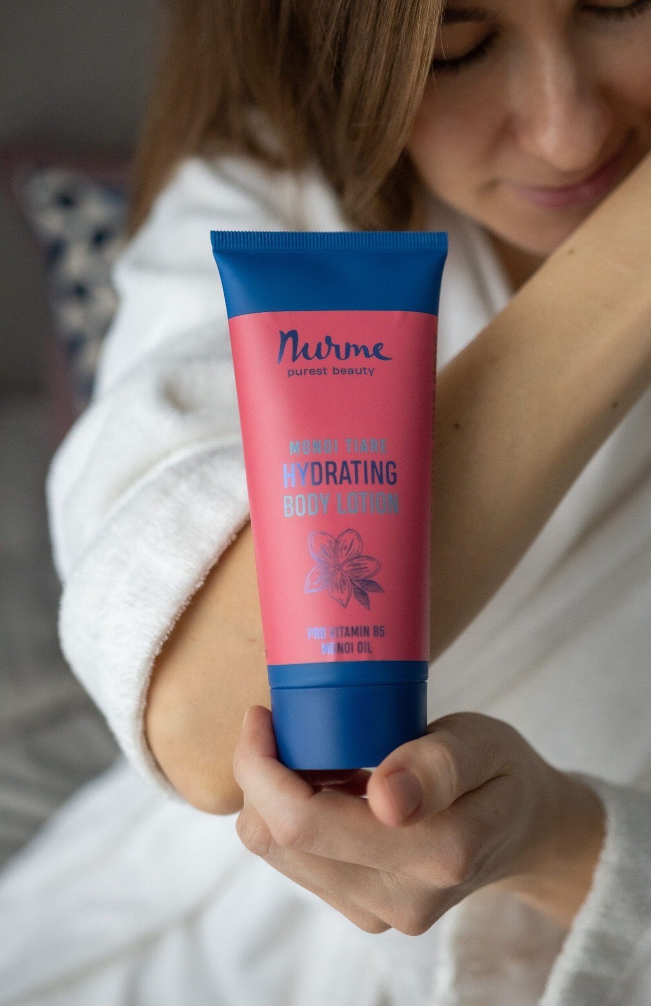5. Woman applying Nurme hydrating body lotion with Monoi oil to arm, shown in lifestyle setting