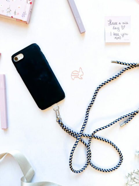 3. Flat lay of SEIK Universal Phone Strap in Sea Edge with black phone case and accessories