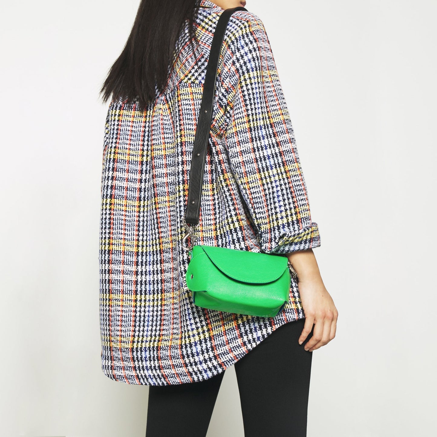 2. Woman wearing Daz Studio neon green leather shoulder bag with plaid shirt, showcasing versatile style