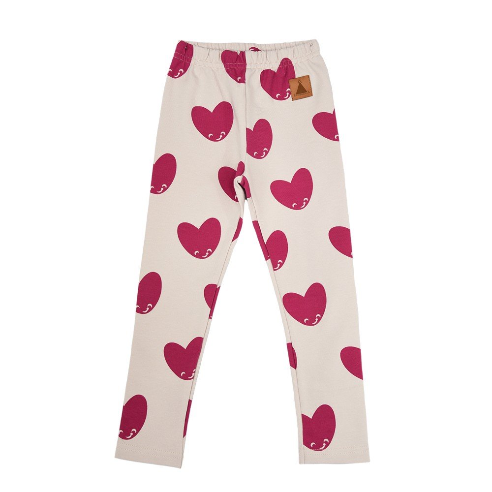 2. Kids' leggings with pink heart pattern on cream background, featuring elastic waistband and Zezuzulla logo patch, shown in studio setting