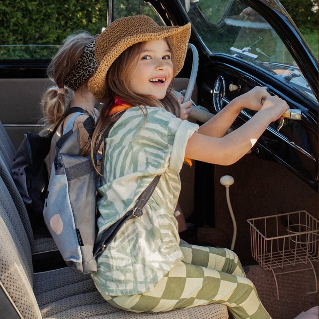 5. Girl driving a car with Muni wolf backpack, capturing playful adventure