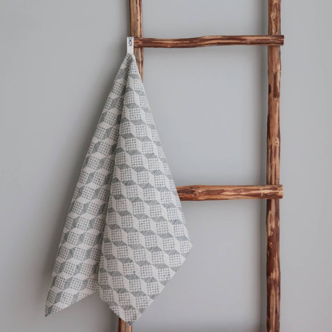 1. Kitchen towel with Virumaa folk art pattern in grey and white, hanging on rustic wooden ladder, showcasing full design
