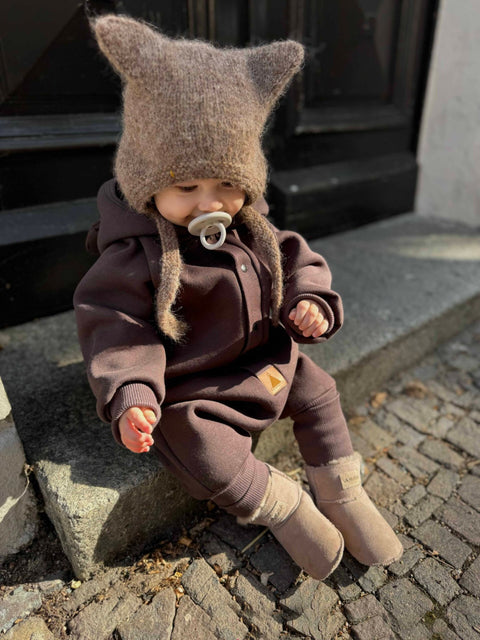 2. Baby in chocolate brown eared jumpsuit with hood sitting on steps