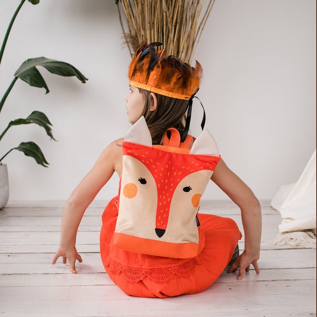 4. Girl sitting with Muni fox backpack, showing back view and comfortable fit