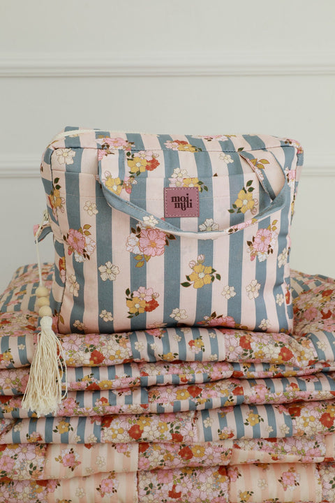 4. Large blue striped makeup bag with floral print and moi mili logo, placed on matching fabric