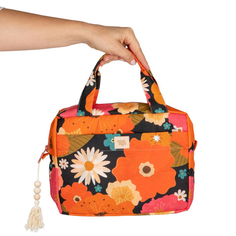 5. Hand holding large floral print makeup bag with tassel, studio background