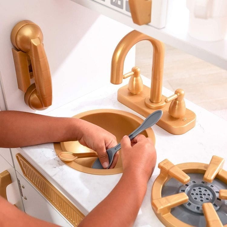 8. Close-up of child washing utensils in gold sink of Angelove play kitchen