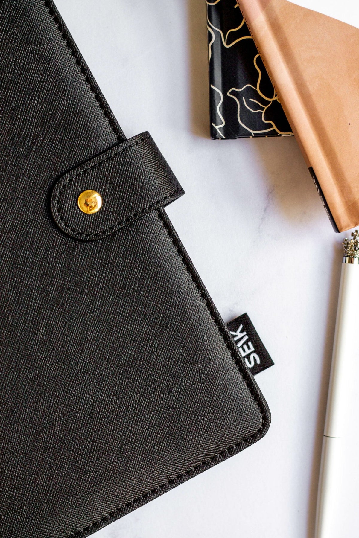 3. Close-up of SEIK Premium Dream Plan Do Notebook's black vegan leather cover with gold button clasp and SEIK branding