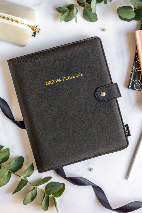 1. SEIK Premium Dream Plan Do Notebook with black vegan leather cover, featuring gold embossed text, surrounded by stationery and greenery