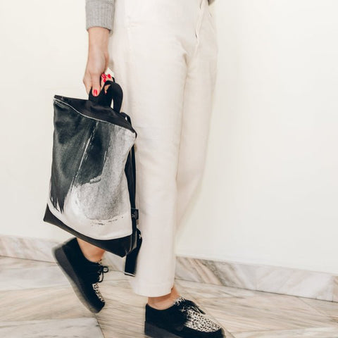 3. Woman holding Muni Black Watercolor backpack, showcasing its design