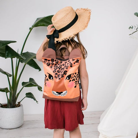 2. Girl wearing Muni leopard backpack, shown from back with straw hat in lifestyle setting