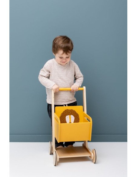 1. Child playing with Trixie Baby Wooden Shopping Cart featuring Mr. Lion design, against a blue wall