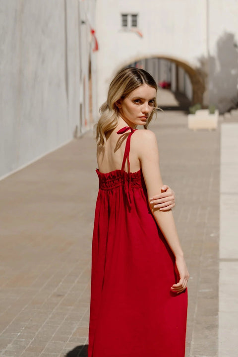 4. Woman in red linen Ballade dress shown from back with tie straps in urban setting