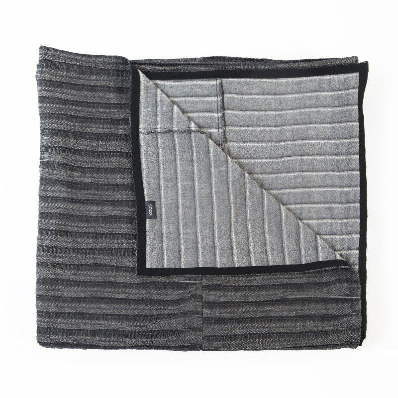 3. Studio shot of folded black and gray linen-cotton bedcover with visible corrugated texture and KOOSdisain label