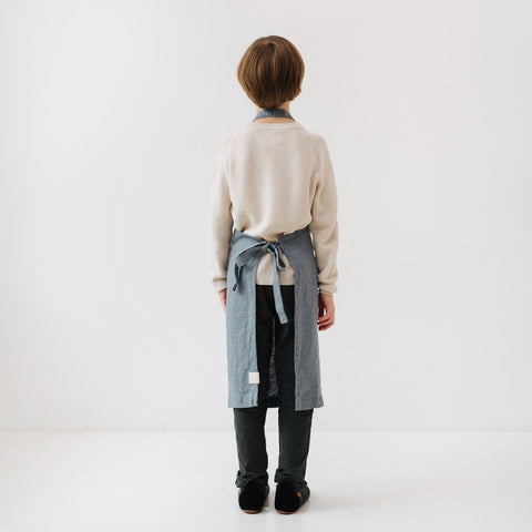 5. Back view of child in blue fog linen apron, highlighting tie closure and length