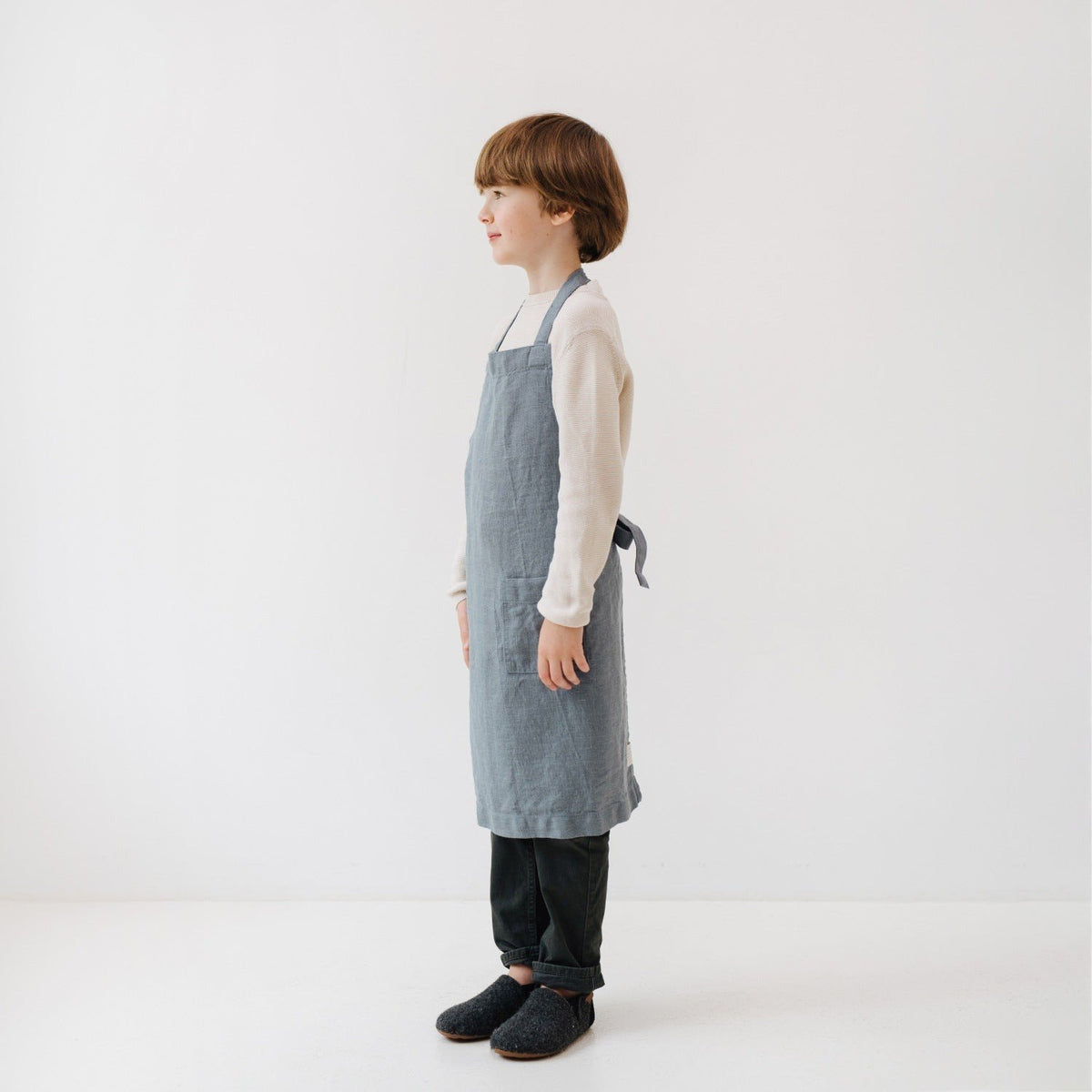 4. Side view of child wearing blue fog linen apron, showing adjustable tie closure