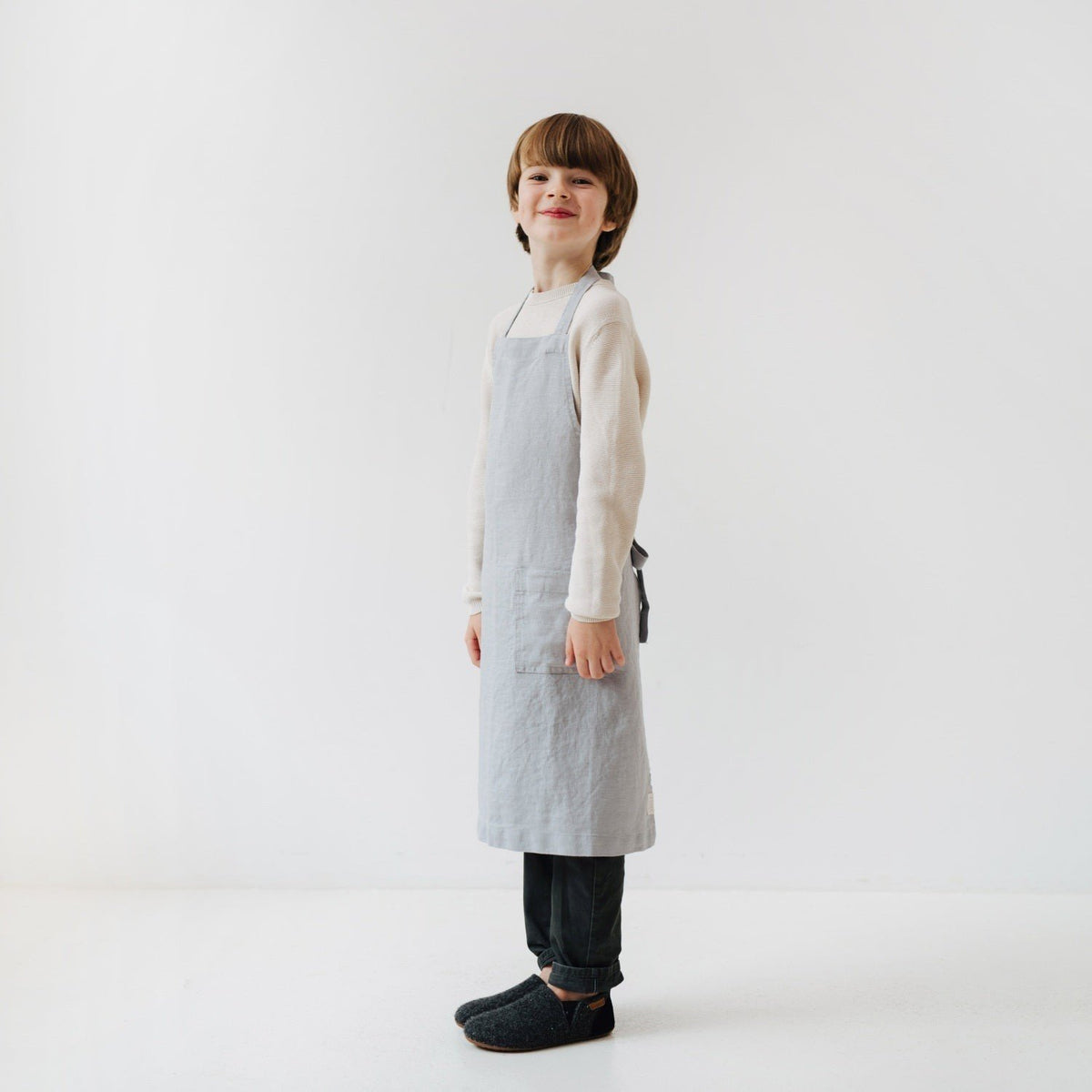 5. Child smiling in light grey linen apron with front pocket