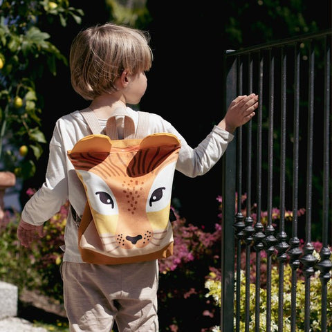 3. Boy wearing Muni lion backpack outdoors near a gate