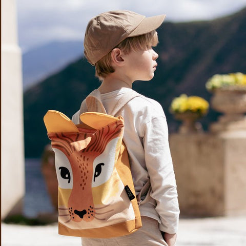 1. Child wearing Muni giraffe backpack in outdoor setting, showcasing playful design and adjustable straps