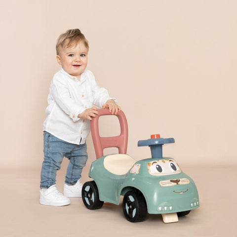 1. Toddler standing with Smoby Little Ride-on Pusher in pastel colors, indoor setting