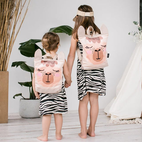 3. Sisters with Muni llama backpacks, showing front design and adjustable straps in lifestyle setting