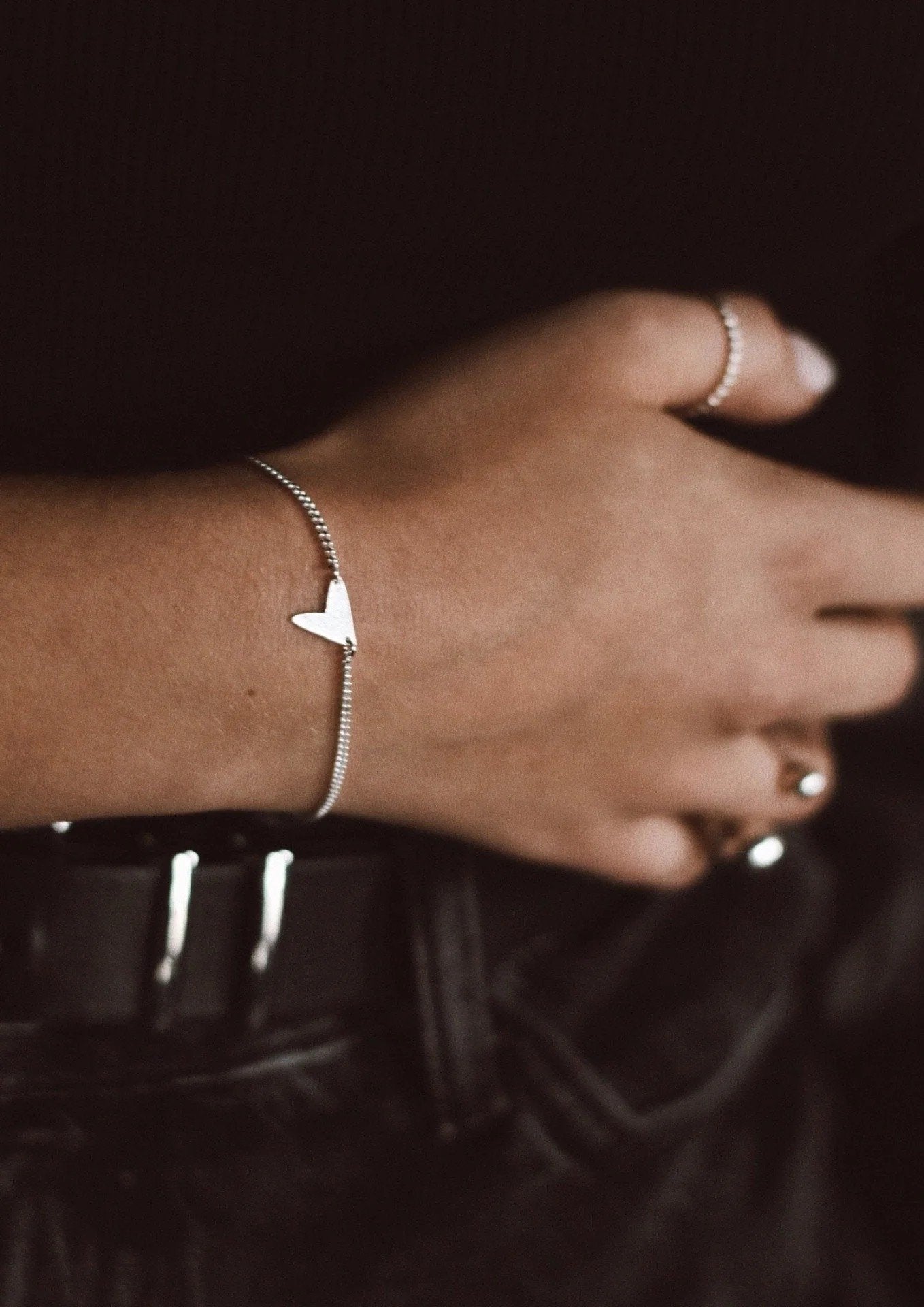 4. Women's Love Bracelet in silver worn with other silver rings, shown on hands in artistic pose