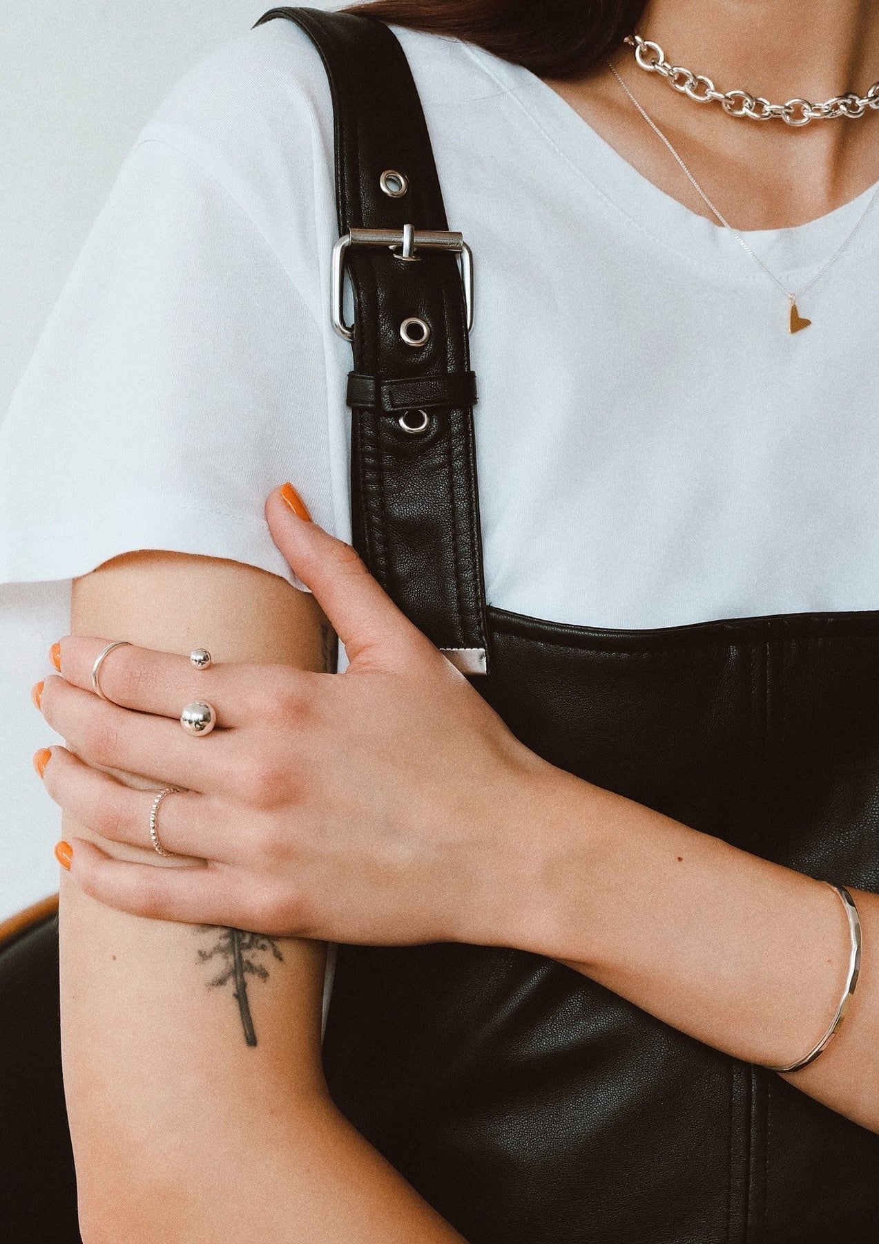 6. Women's Love Necklace in gold by NO MORE, styled with a black leather overall and white tee