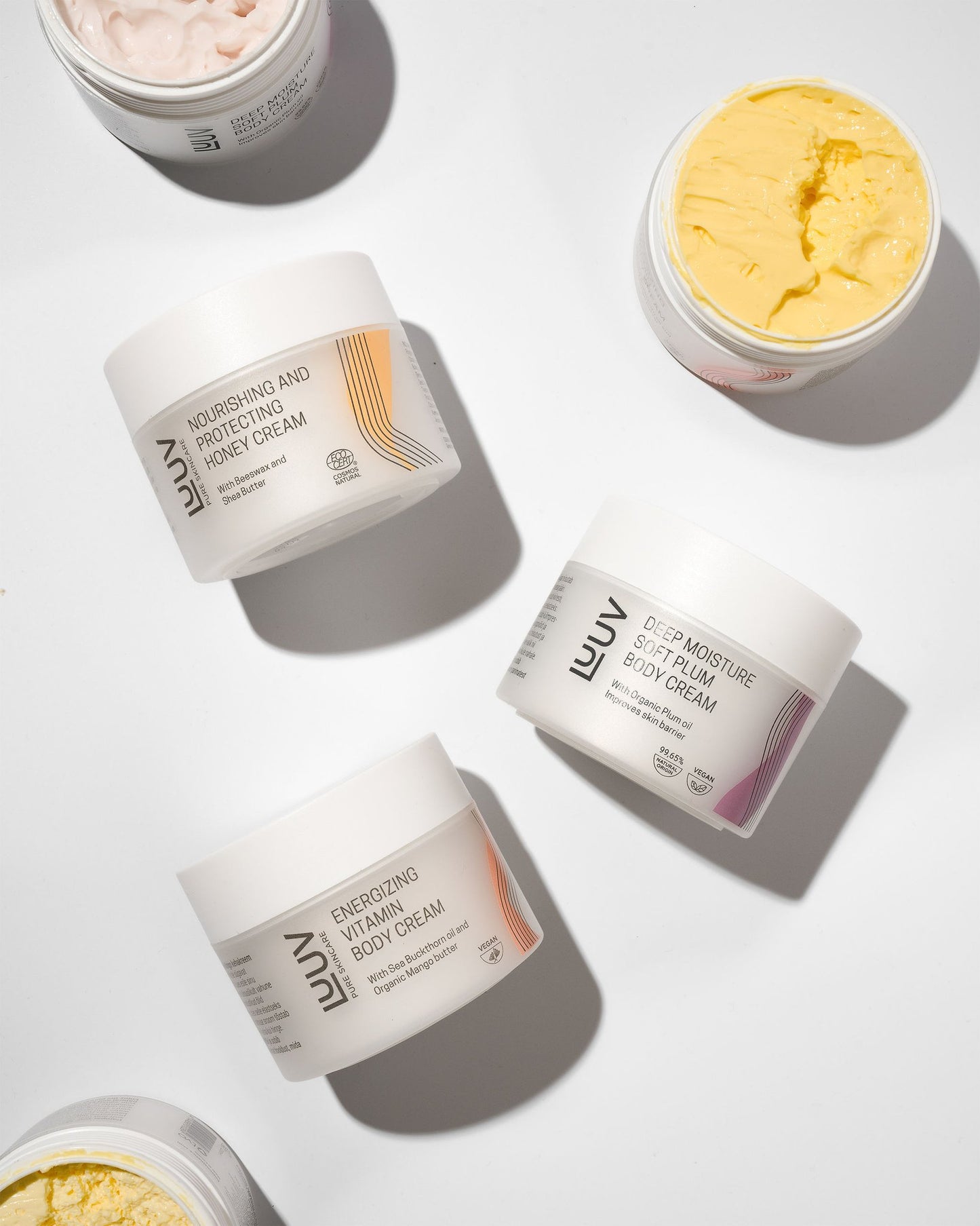 4. Flat lay of LUUV body creams including Nourishing and Protecting Honey Cream, Deep Moisture Soft Plum, and Energizing Vitamin Creams, showing textures