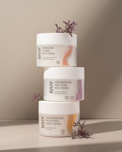 1. LUUV body cream collection featuring Nourishing and Protecting Honey Cream, Deep Moisture Soft Plum, and Energizing Vitamin Creams, styled with flowers