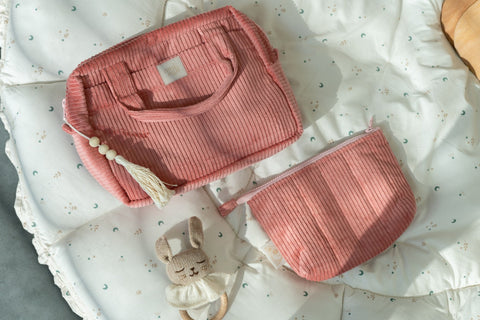 2. Coral makeup bag set on a quilted blanket with a toy rabbit, showcasing texture and design