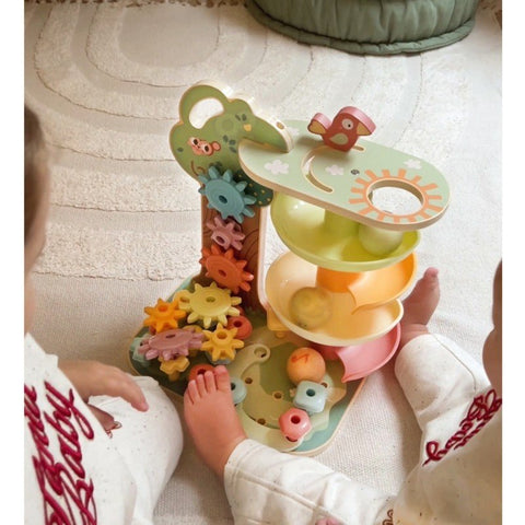 1. Two toddlers playing with Woopie Montessori 4-in-1 activity tree on a carpeted floor, featuring a marble run, shape sorter, spinning gears, and bead maze.