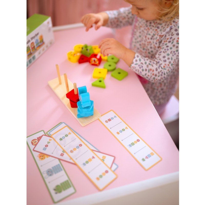 6. Child arranging colorful blocks on Montessori puzzle pyramid with pattern cards on pink table