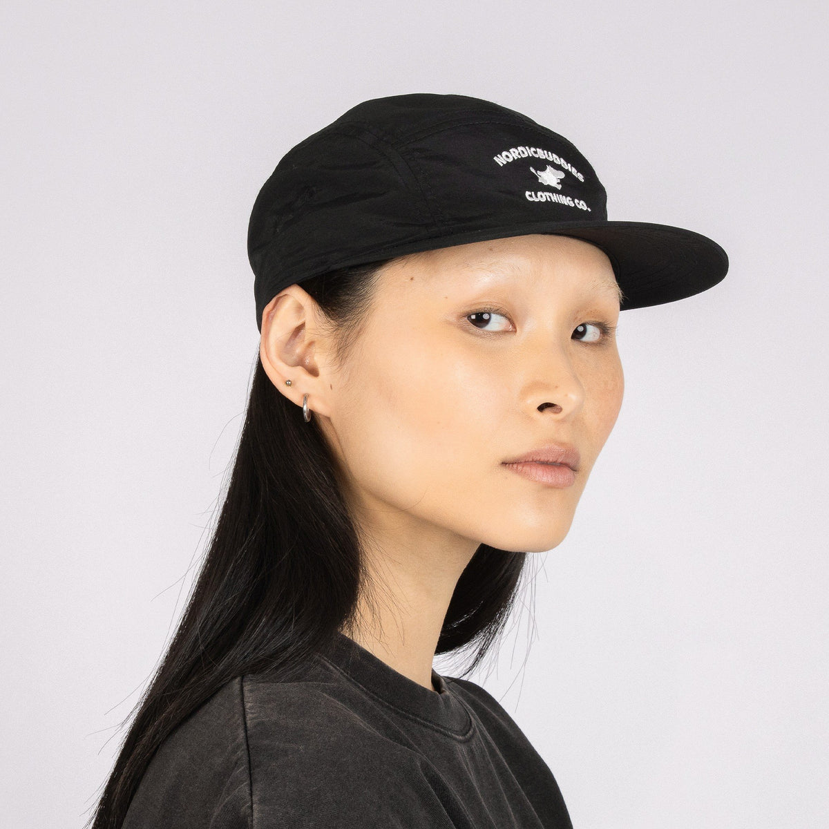 3. Side view of unisex black Moomintroll Adventure 5-panel cap worn by female model